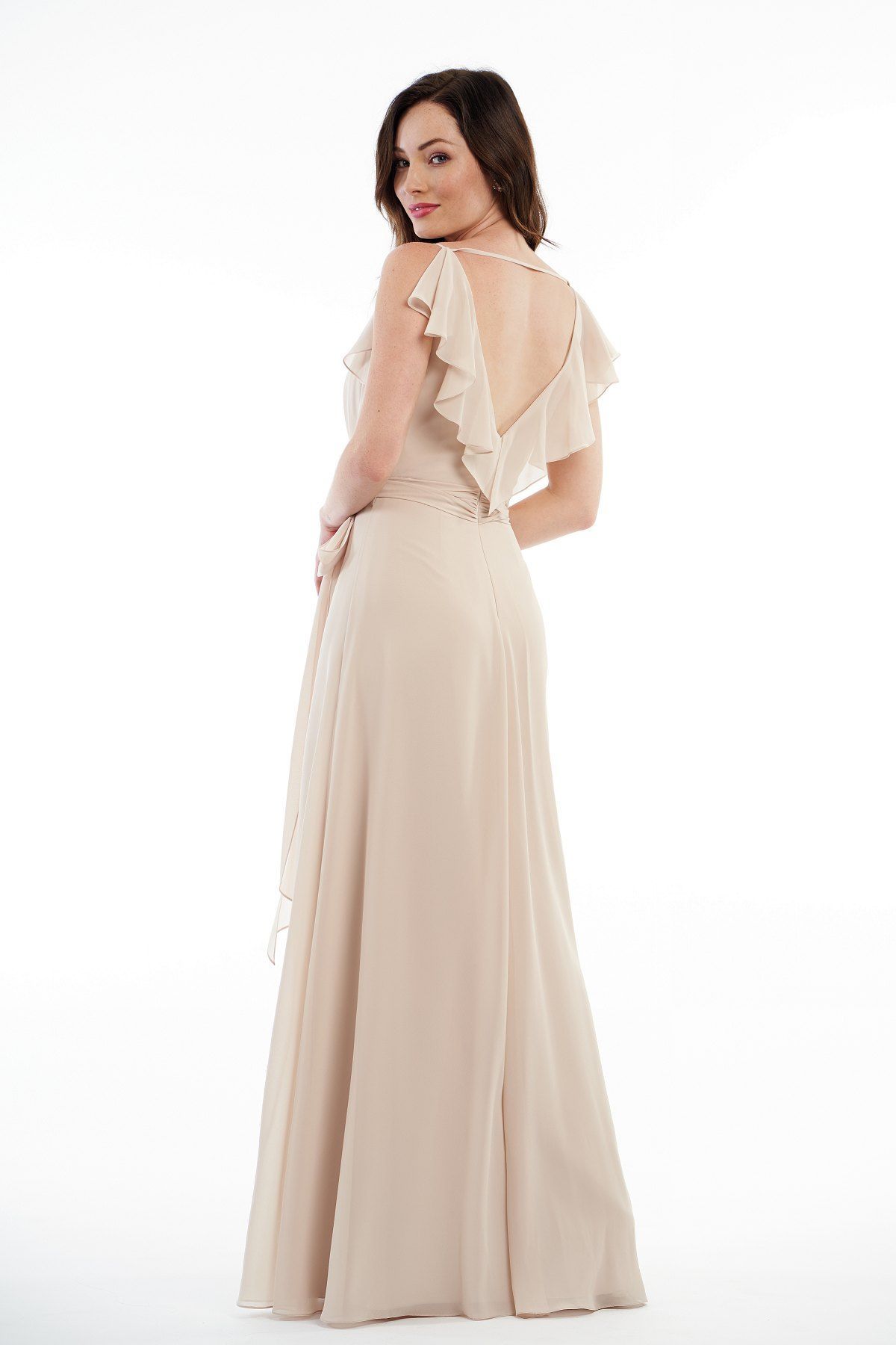 Woman in beige formal dress, looking over her shoulder, on white background.