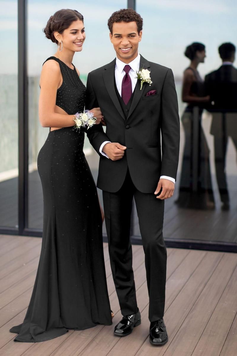 Couple in formal attire; man in black suit, woman in black gown, smiling, at an event.