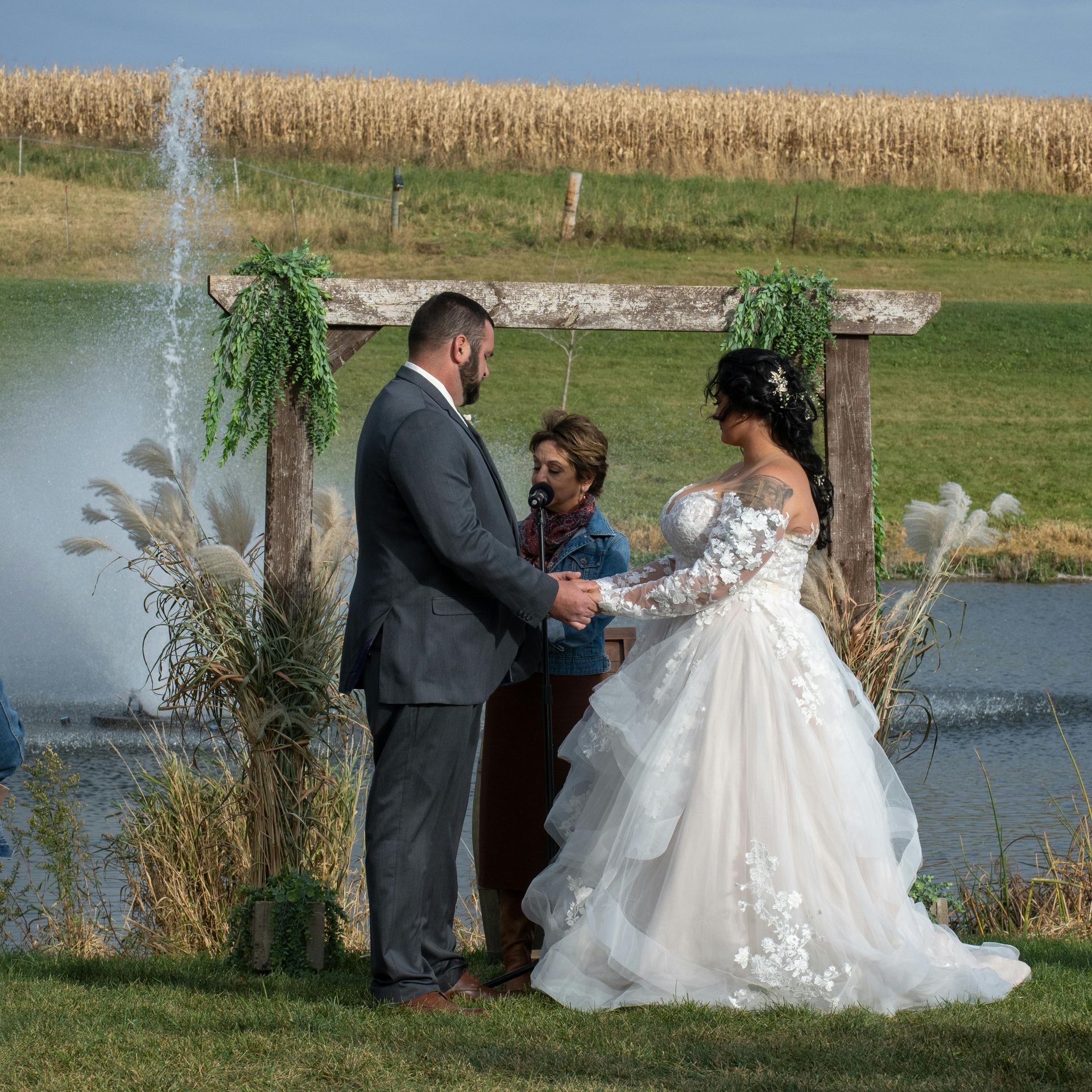 Woman in formal gown, seated on pink couch, under neon sign that says