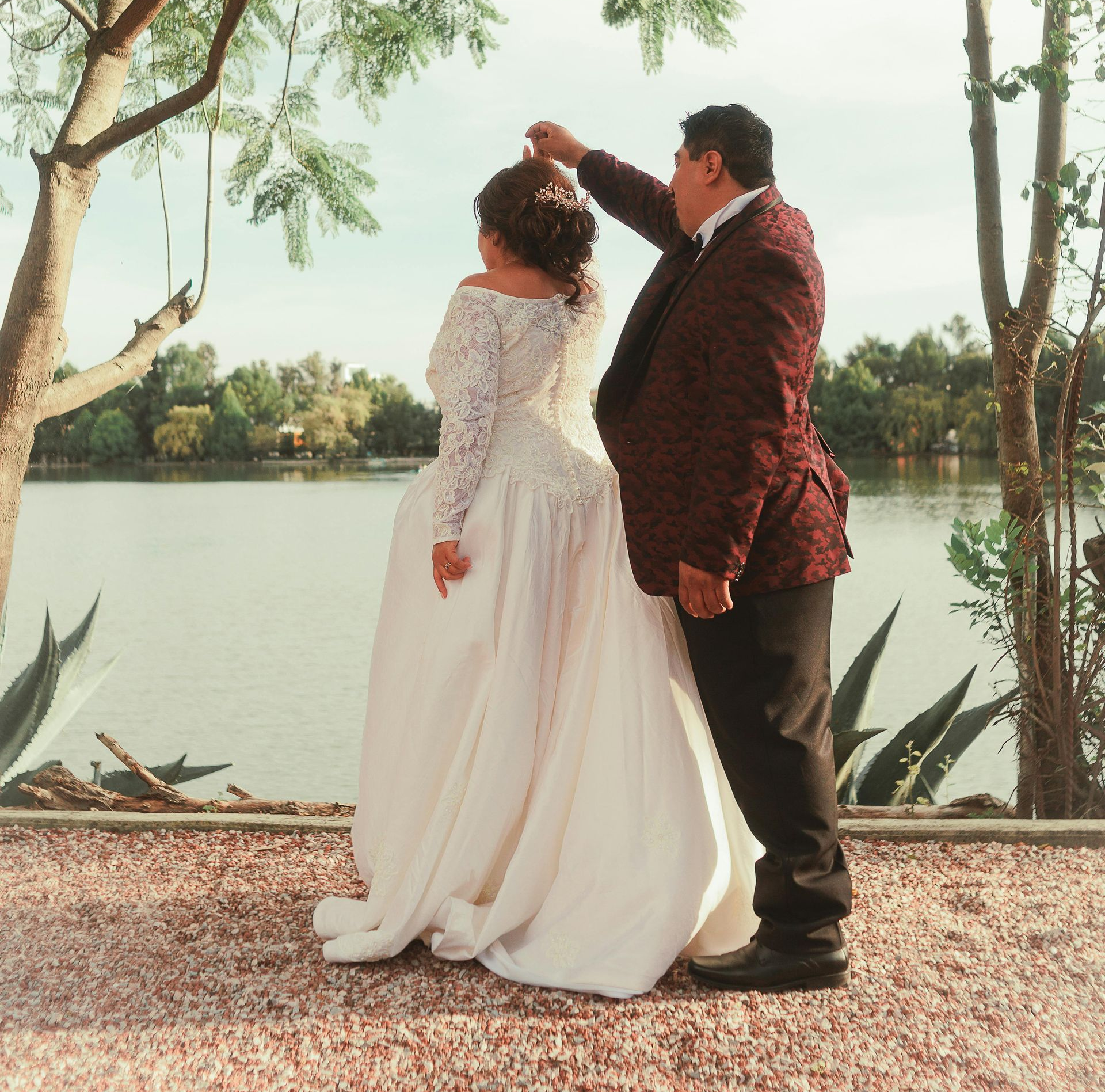 Woman in a white off-shoulder wedding dress smiles in a bridal shop.