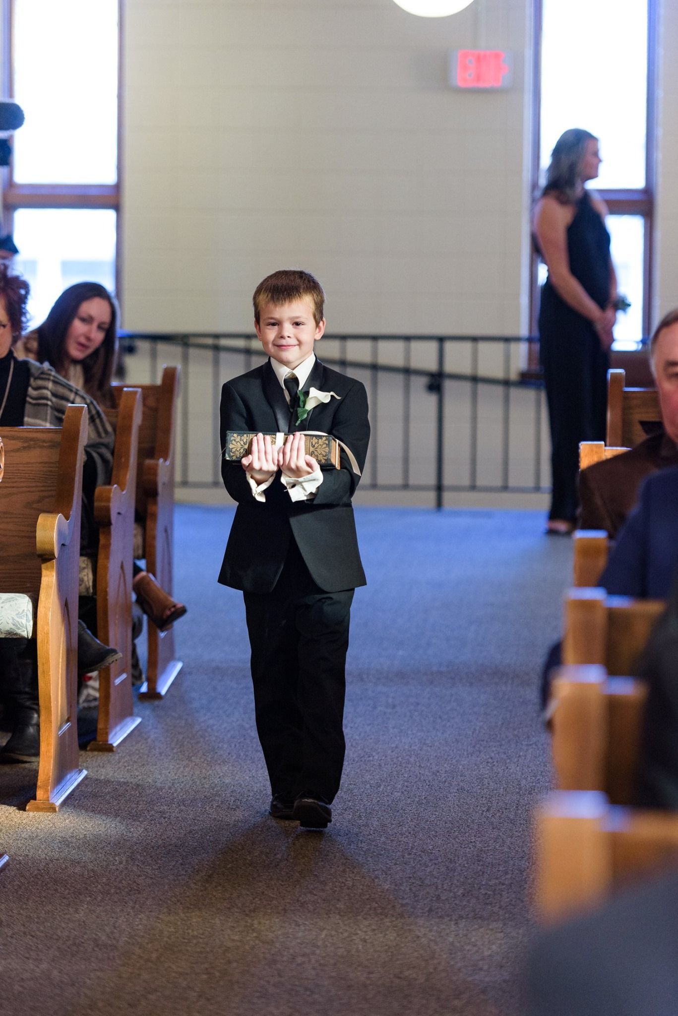 Woman in formal gown, seated on pink couch, under neon sign that says
