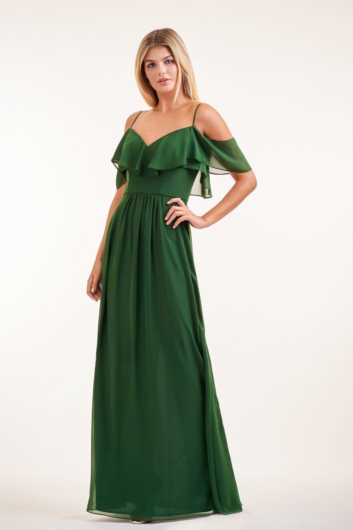 Woman in a dark green, off-shoulder formal dress, posing against a light background.