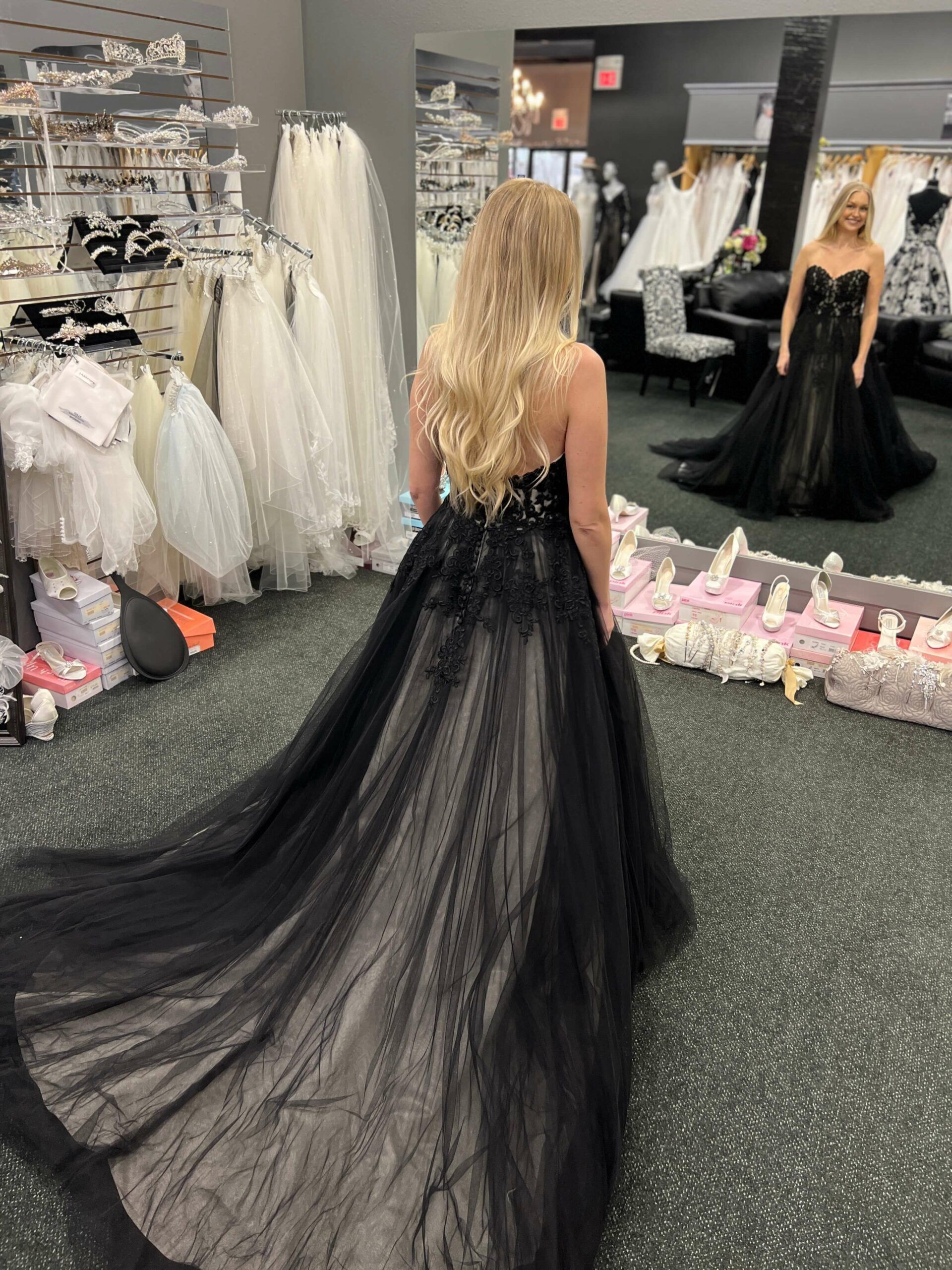 Woman in black wedding dress in a bridal shop, looking in a mirror.