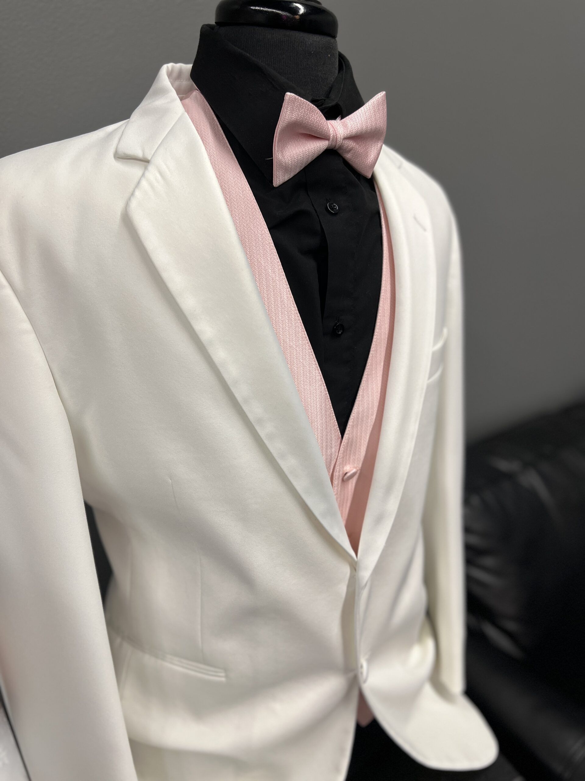 White suit jacket, pink vest and bow tie, black shirt. Formalwear.