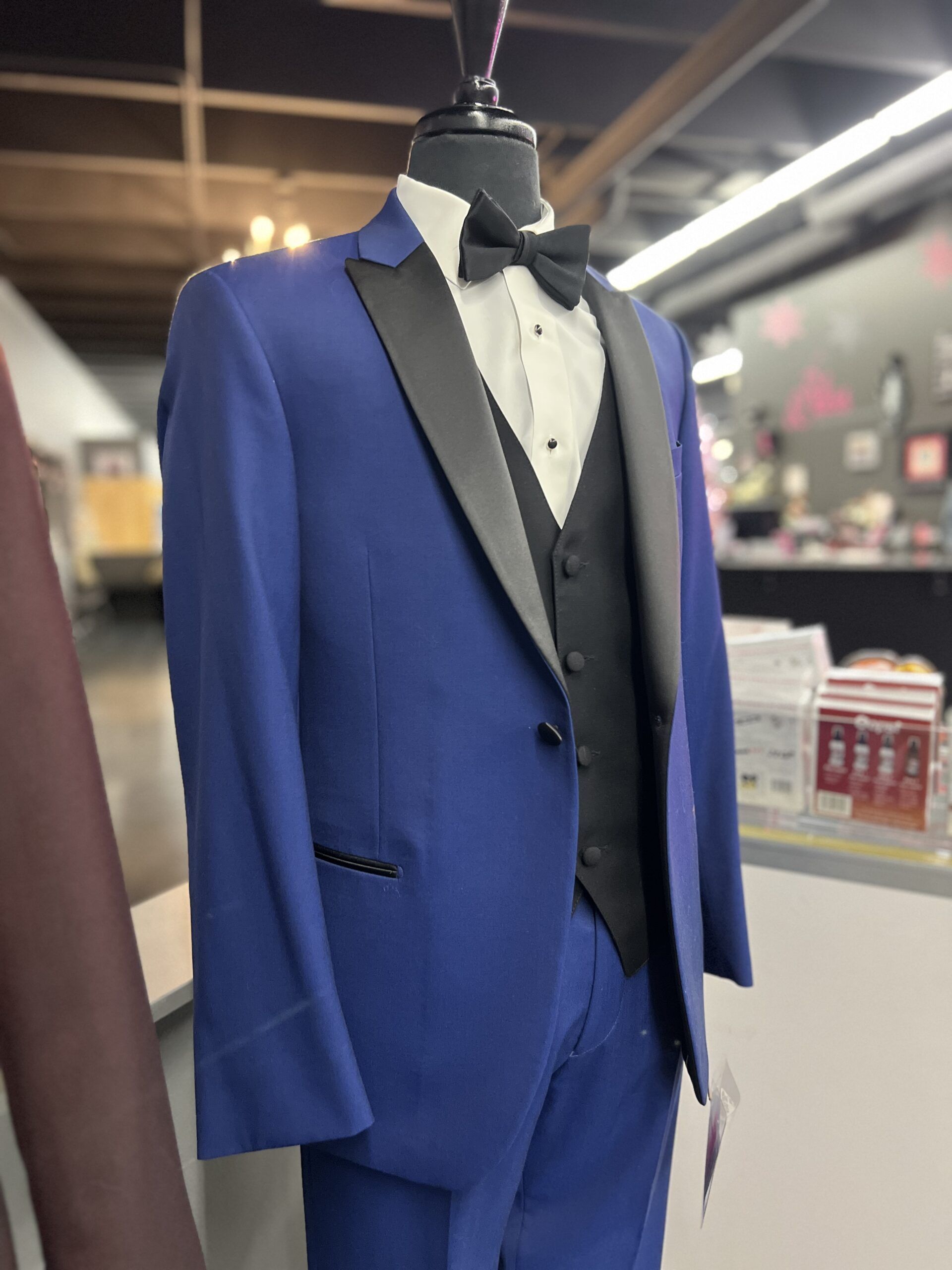 Blue tuxedo on a mannequin. Black lapels and bow tie. Vest and white dress shirt.