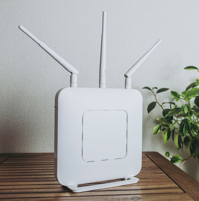 White Wi-fi Router With Three Antennas on Wooden Surface — Ralph Ottmann Electrical in Pomona, QLD