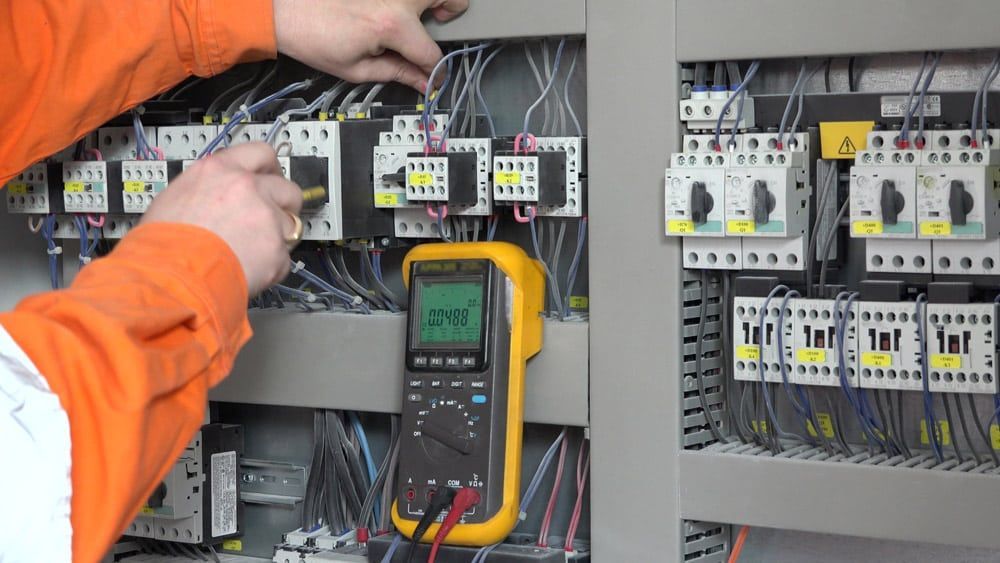 Electrician Using a Multimeter in a Control Panel — Ralph Ottmann Electrical in Pomona, QLD