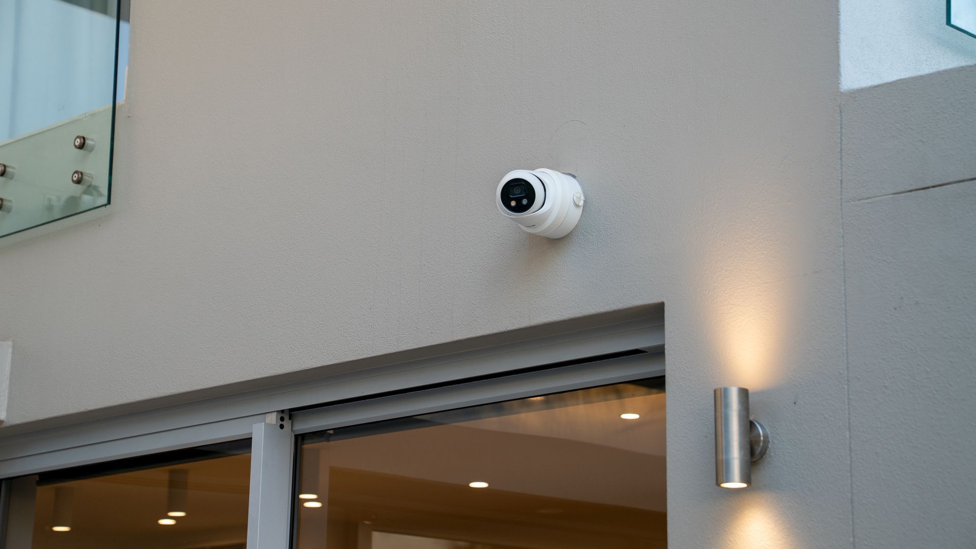 White Security Camera Mounted on a Beige Exterior Wall — Ralph Ottmann Electrical in Pomona, QLD