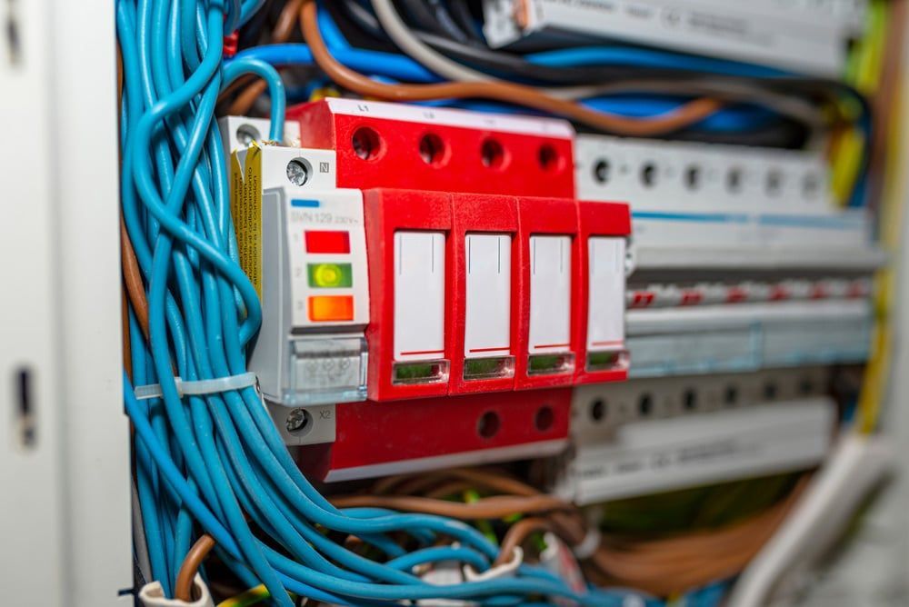 Electrical Panel With Red Surge Protector and Colored Wires — Ralph Ottmann Electrical in Pomona, QLD