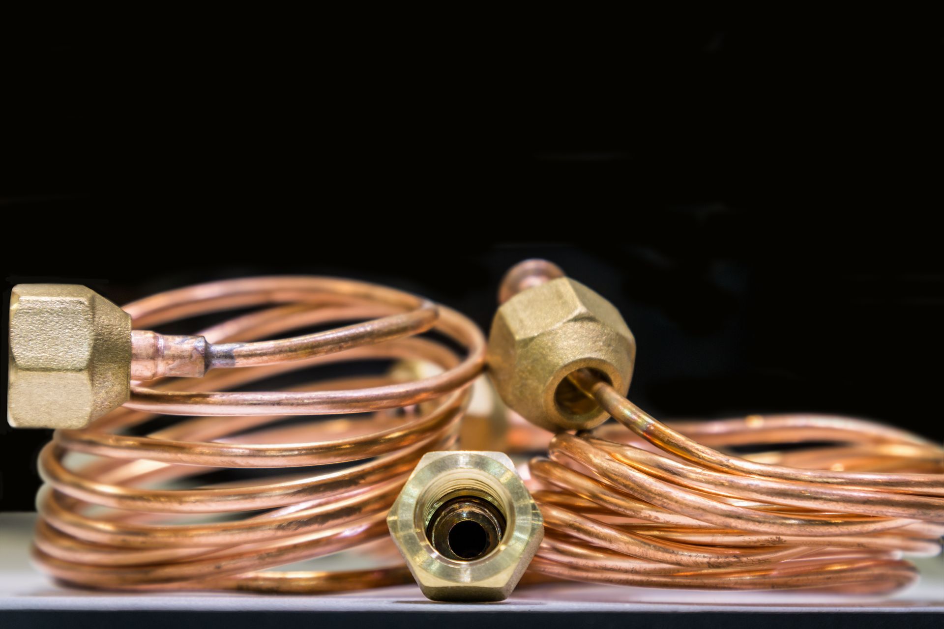 coiled copper tubing with brass fittings, arranged against a black background. coiled copper tubing with brass fittings, arranged against a black background.