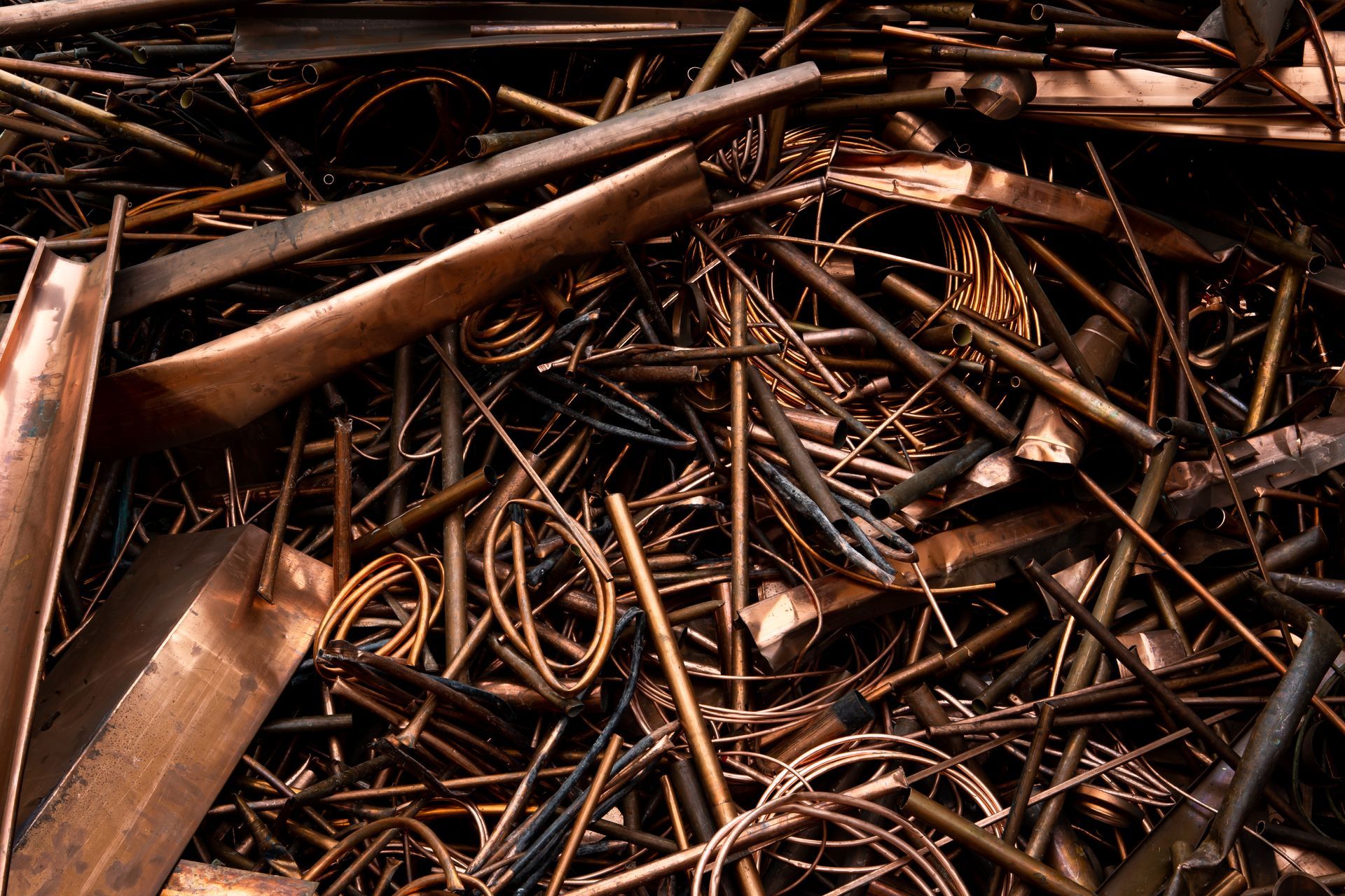 Pile of copper scrap wires and metal tubes at a recycling yard.