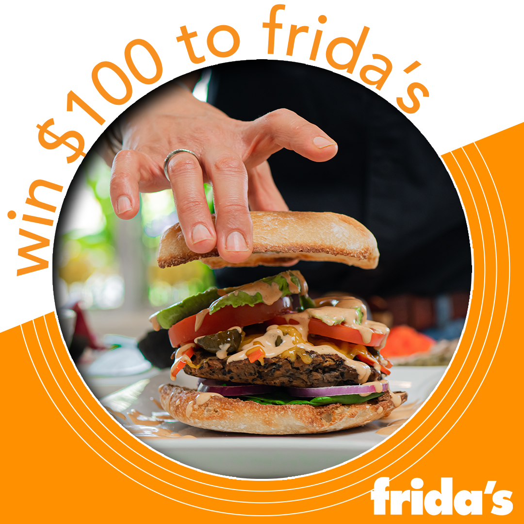 A person is holding a hamburger on a plate with a sign that says $ 100 to frida 's