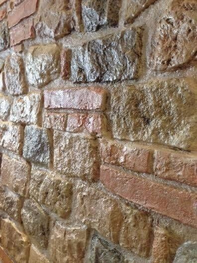 Primo piano di un muro di mattoni, con un mix di mattoni e malta color marrone chiaro e rossastro.