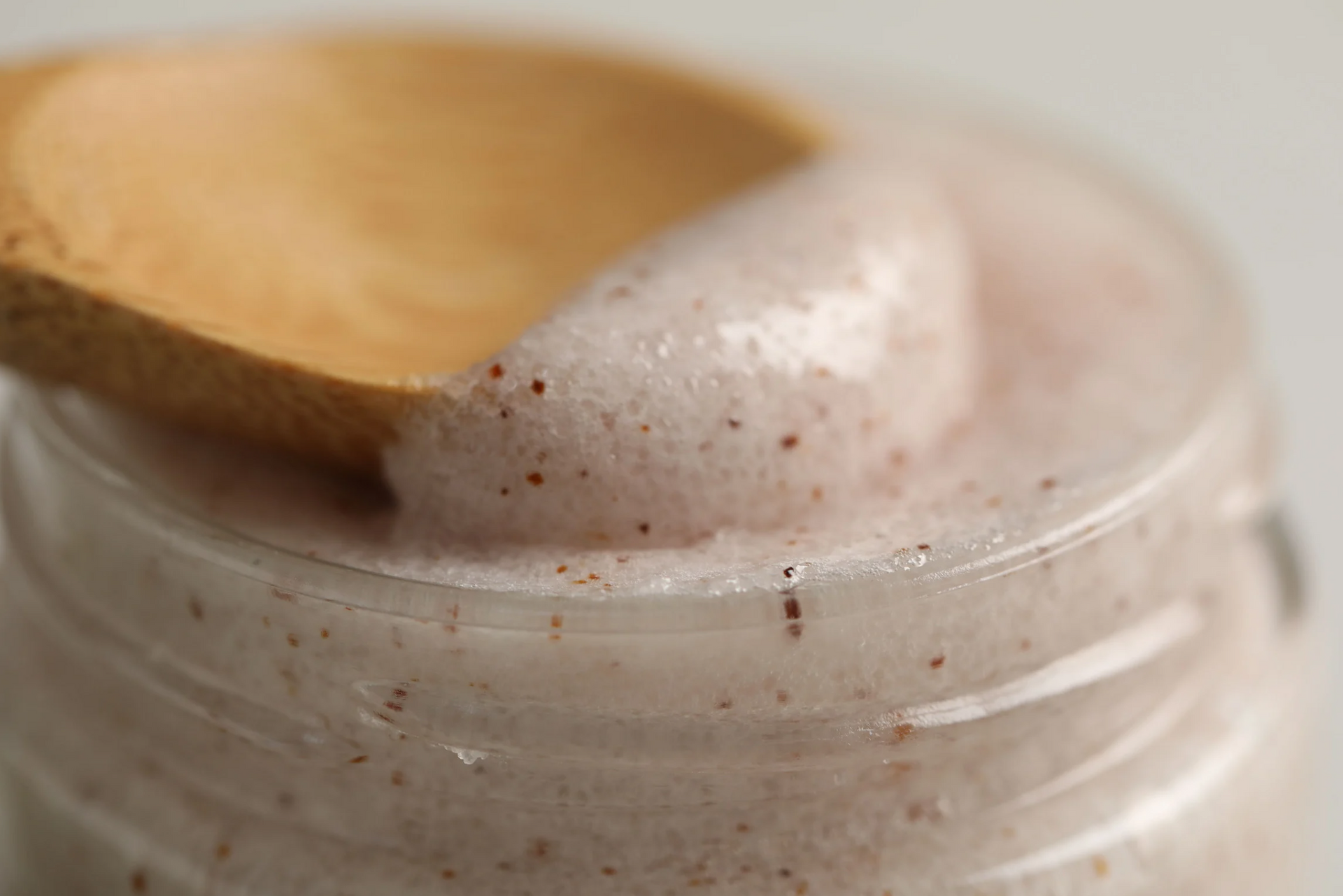 Person receiving neck massage, face turned upwards, hands of masseuse on neck. White setting.