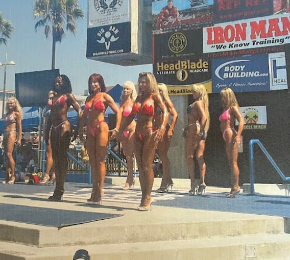 A group of women in bikinis stand on a stage in front of a sign that says iron man