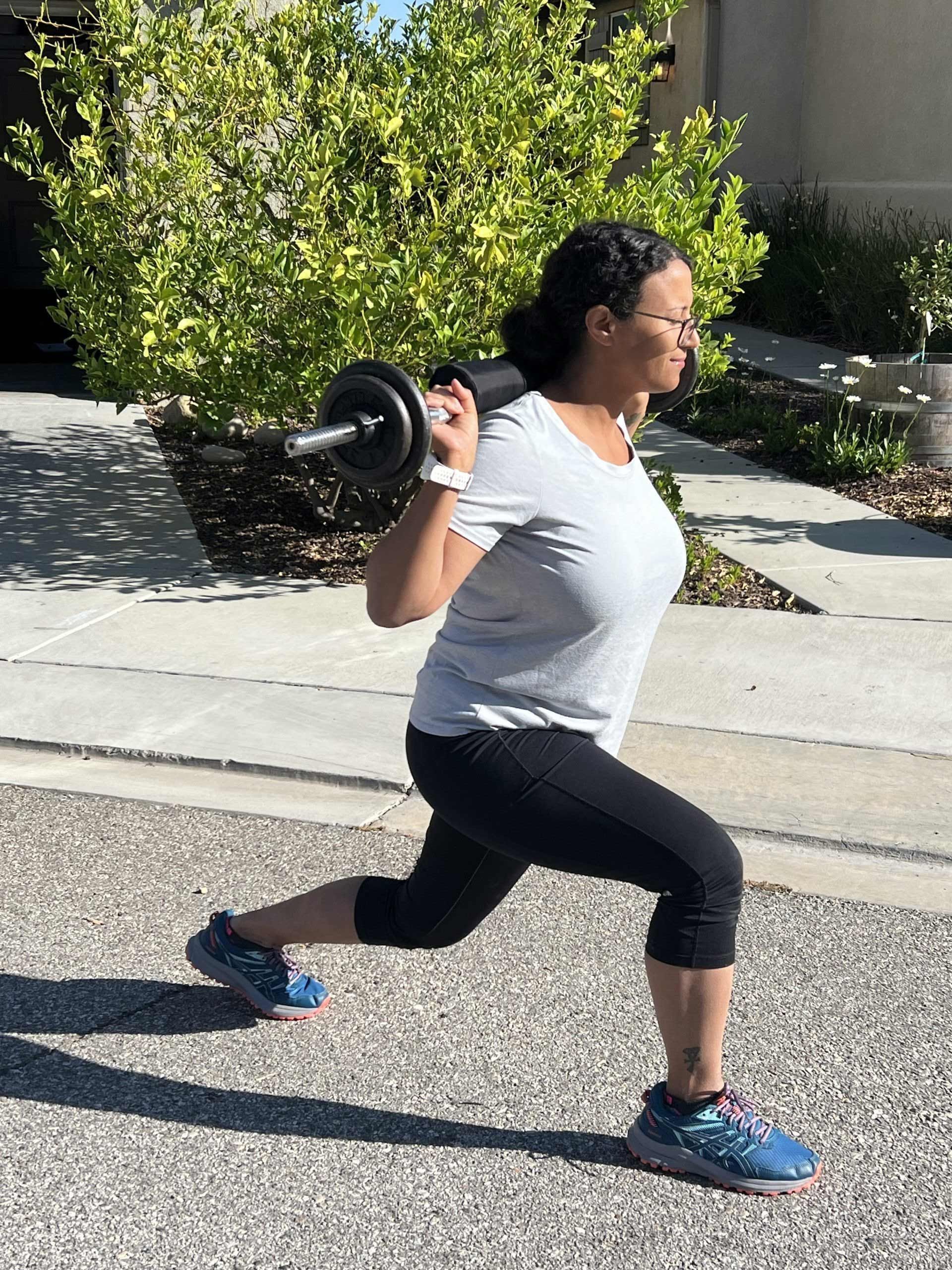 A woman is doing squats with a barbell on her back.