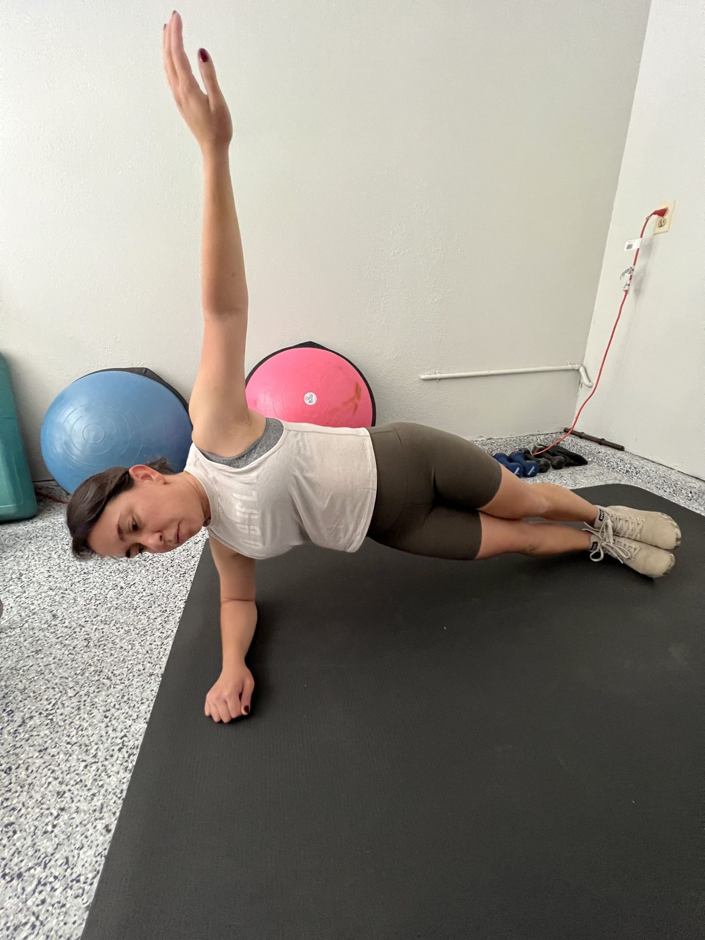 A woman is doing a side plank on a yoga mat.
