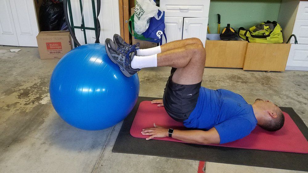 A man is doing exercises with an exercise ball in a garage.