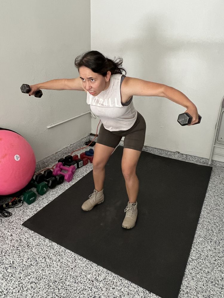 A woman is doing exercises with dumbbells in a gym.