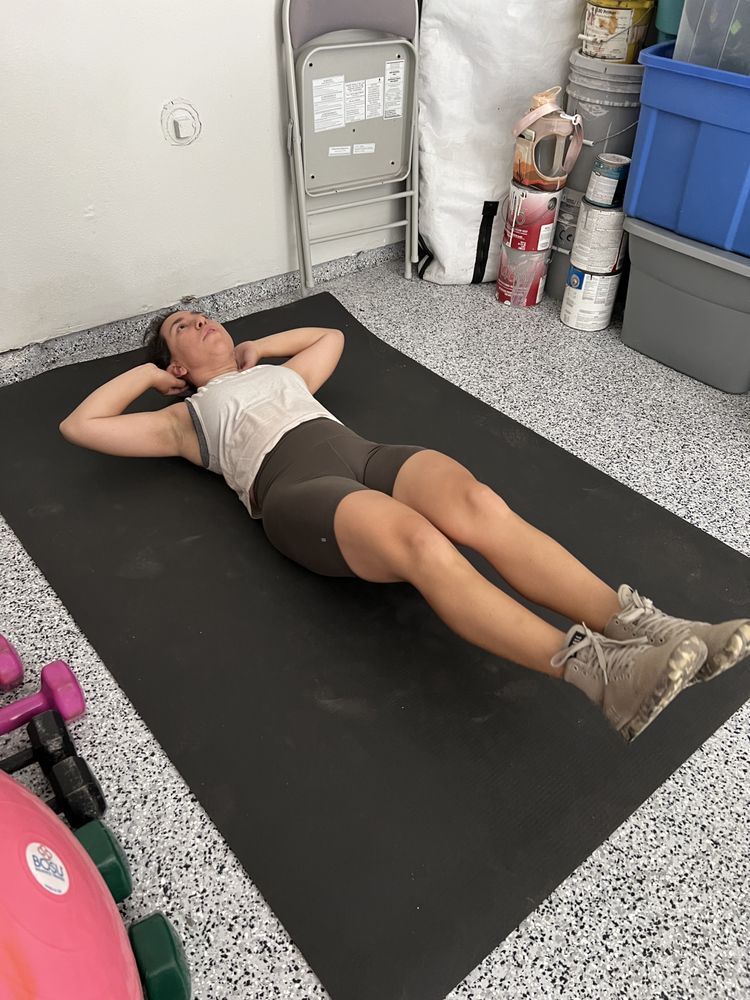 A woman is laying on a yoga mat in a garage.