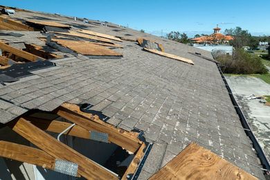Damaged roof with missing shingles and exposed wood after storm damage
