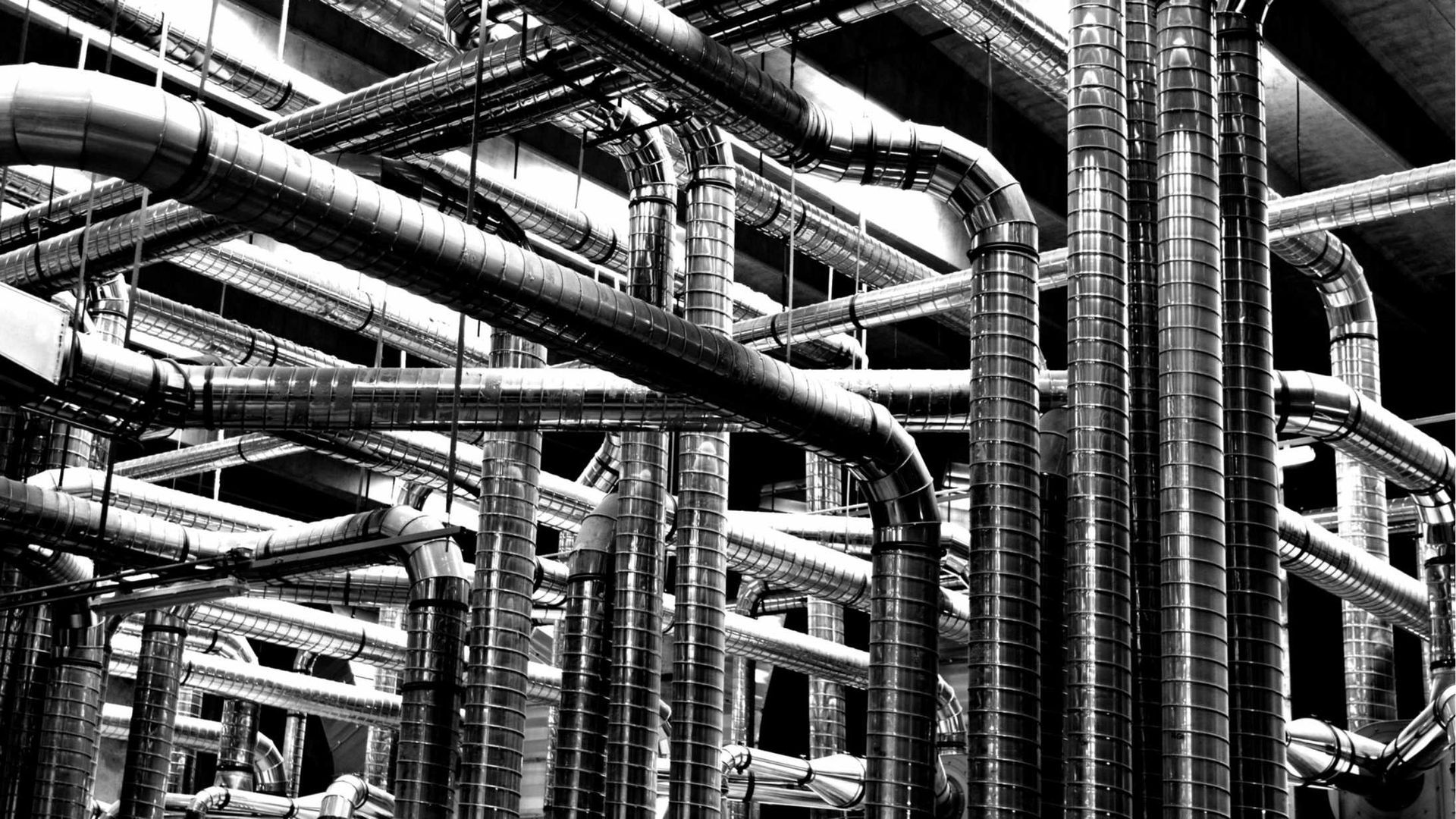 A black and white photo of a bunch of pipes in a factory.