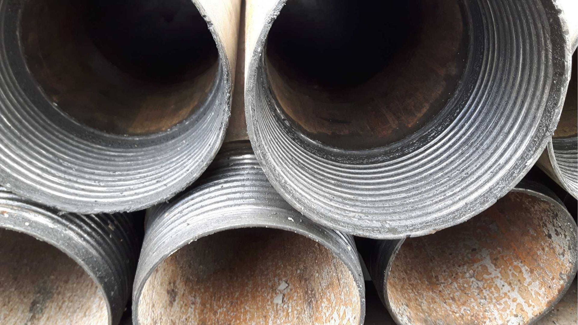 A close up of a pile of metal pipes stacked on top of each other.