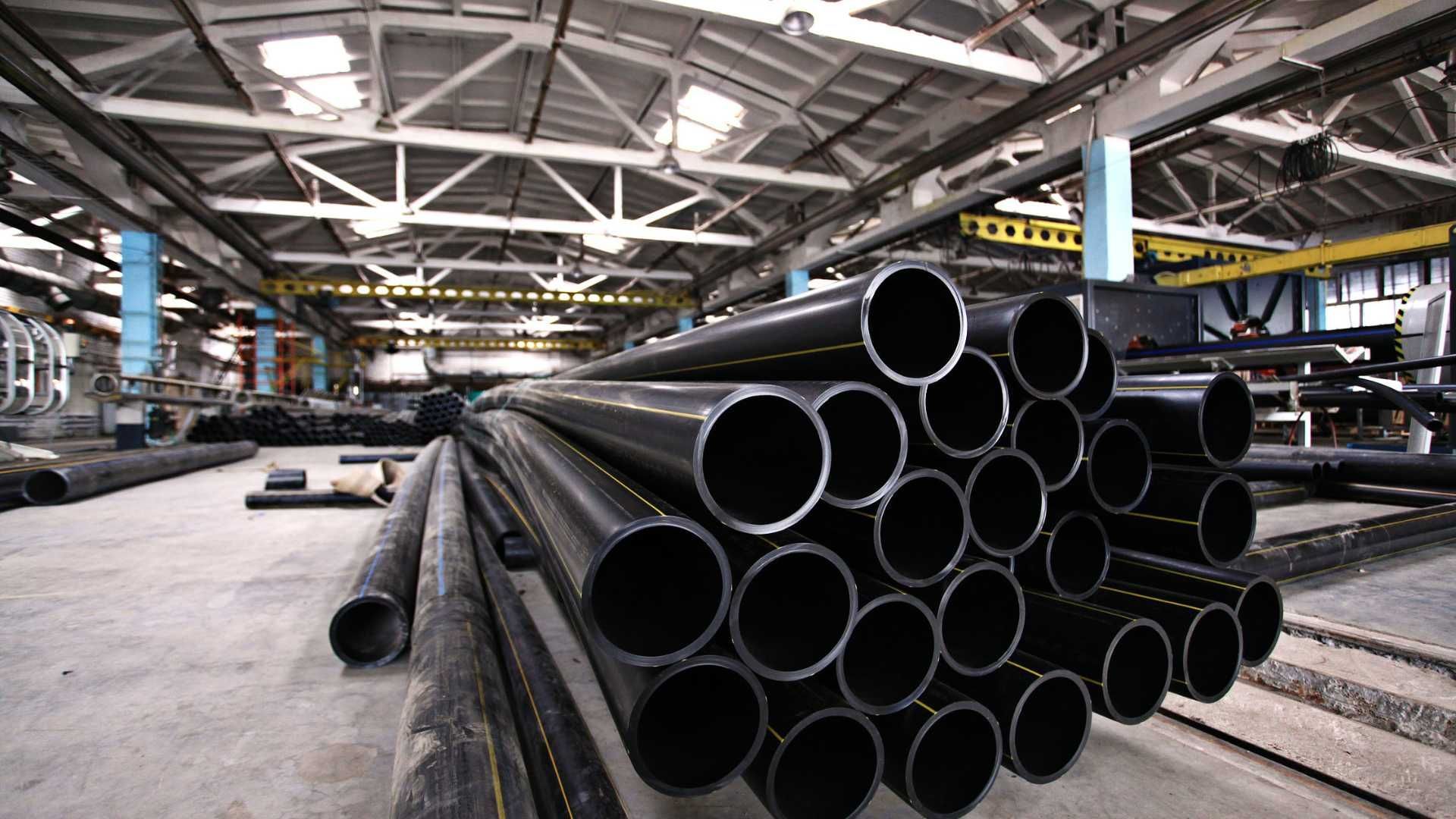 A warehouse filled with lots of metal pipes stacked on top of each other.