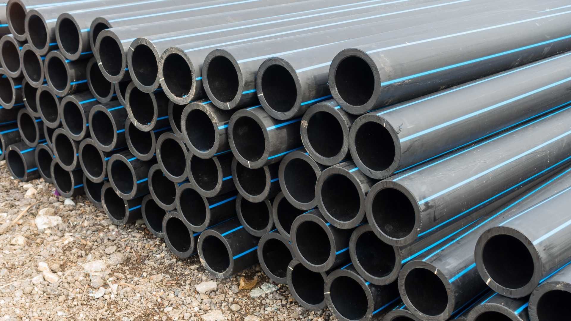 A pile of black pipes with blue stripes are stacked on top of each other.