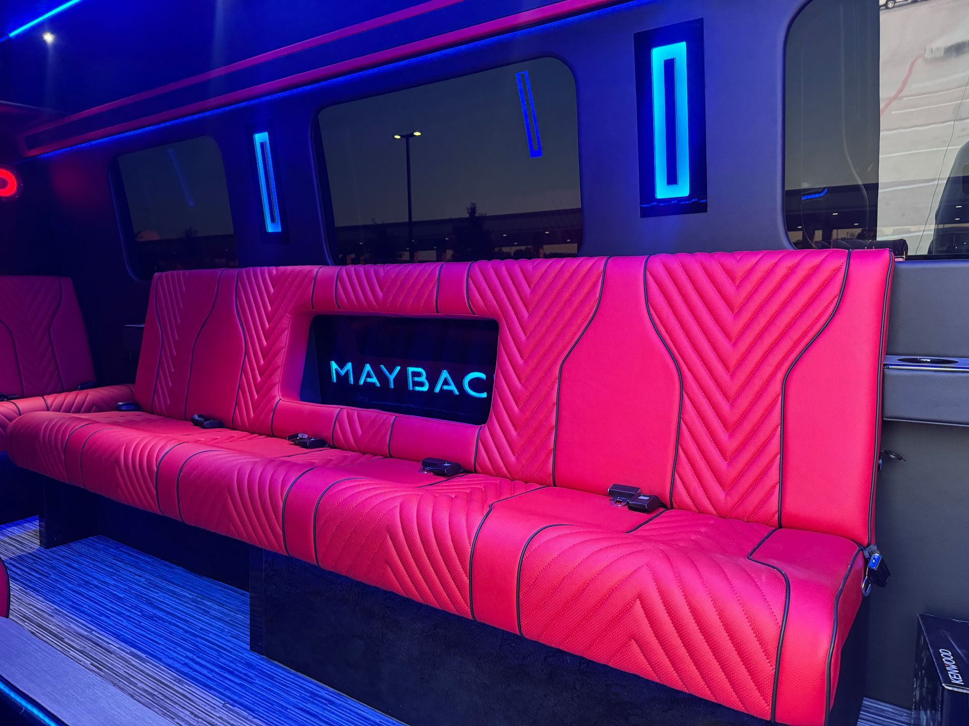 Interior of a luxury party bus with seating, screens, and colorful LED lighting.