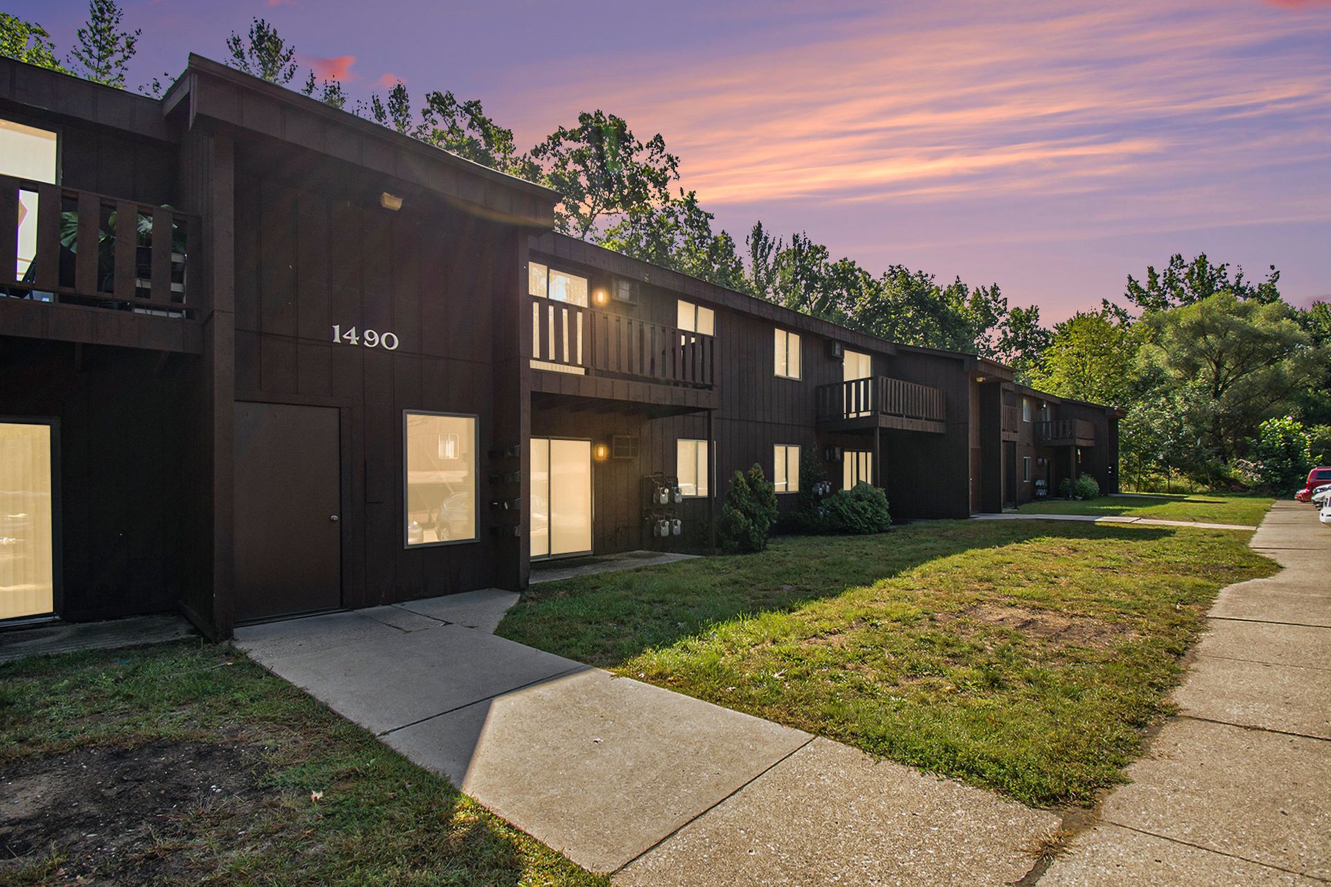 Dark brown apartment complex at dusk with pink and purple sky.