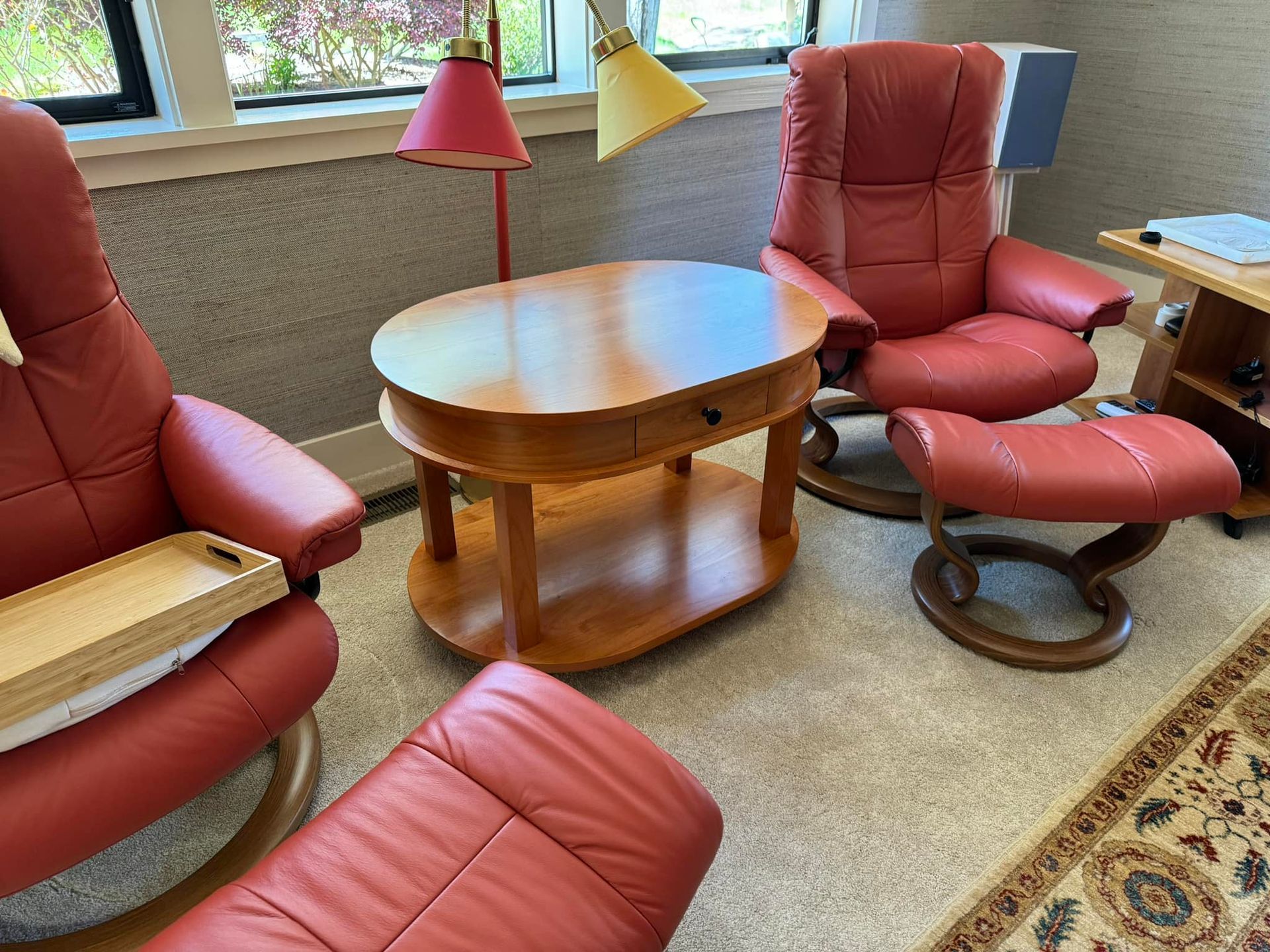 A living room with red leather chairs , a coffee table , and a lamp.