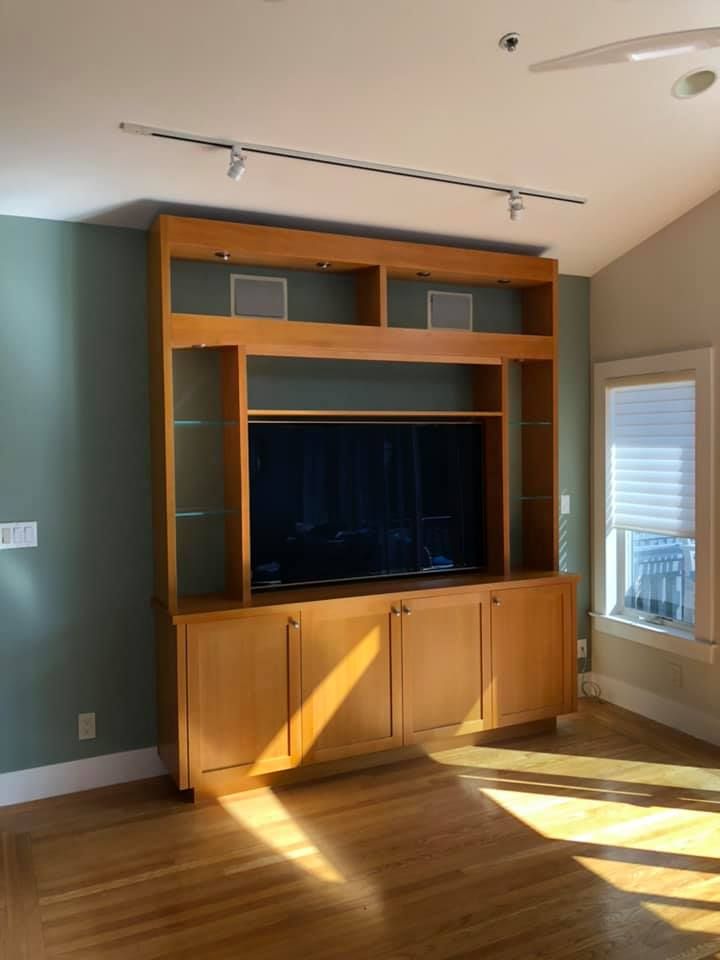 A living room with a large entertainment center and a flat screen tv.