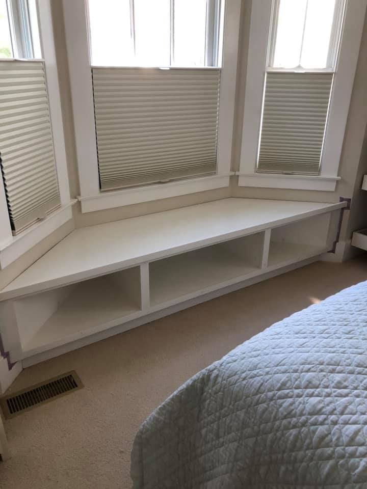 A bedroom with a window seat and a bed.