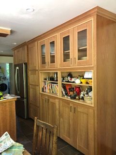 A kitchen with lots of wooden cabinets and glass doors