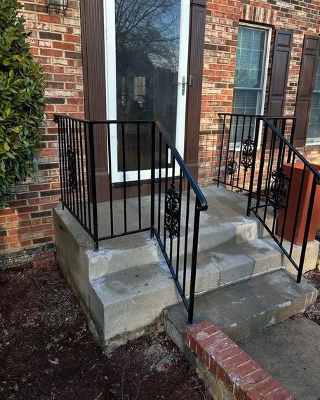 A brick house with a wrought iron railing on the porch