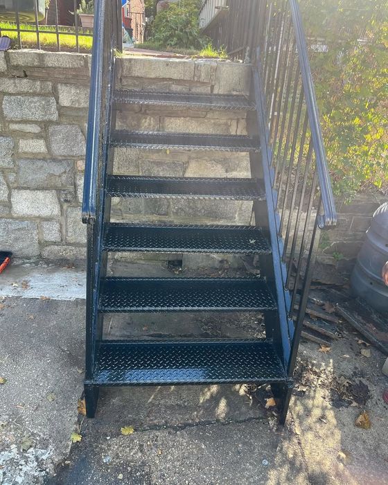 A set of black metal stairs with a blue railing.