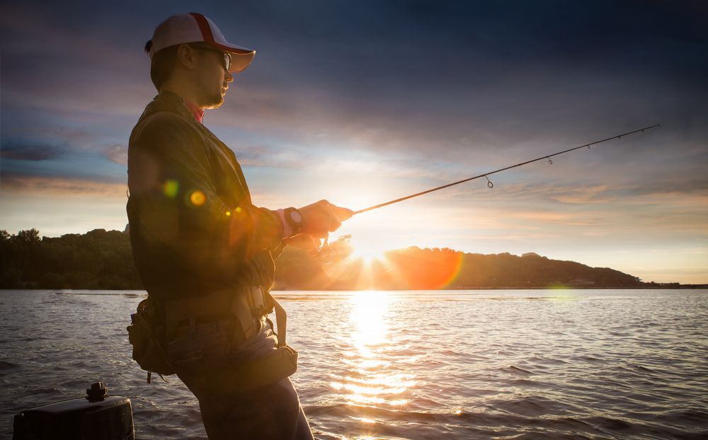 Man Fishing With a Rod at Sunset Over a Calm Lake — EyeMax EyeCare in Cessnock, NSW