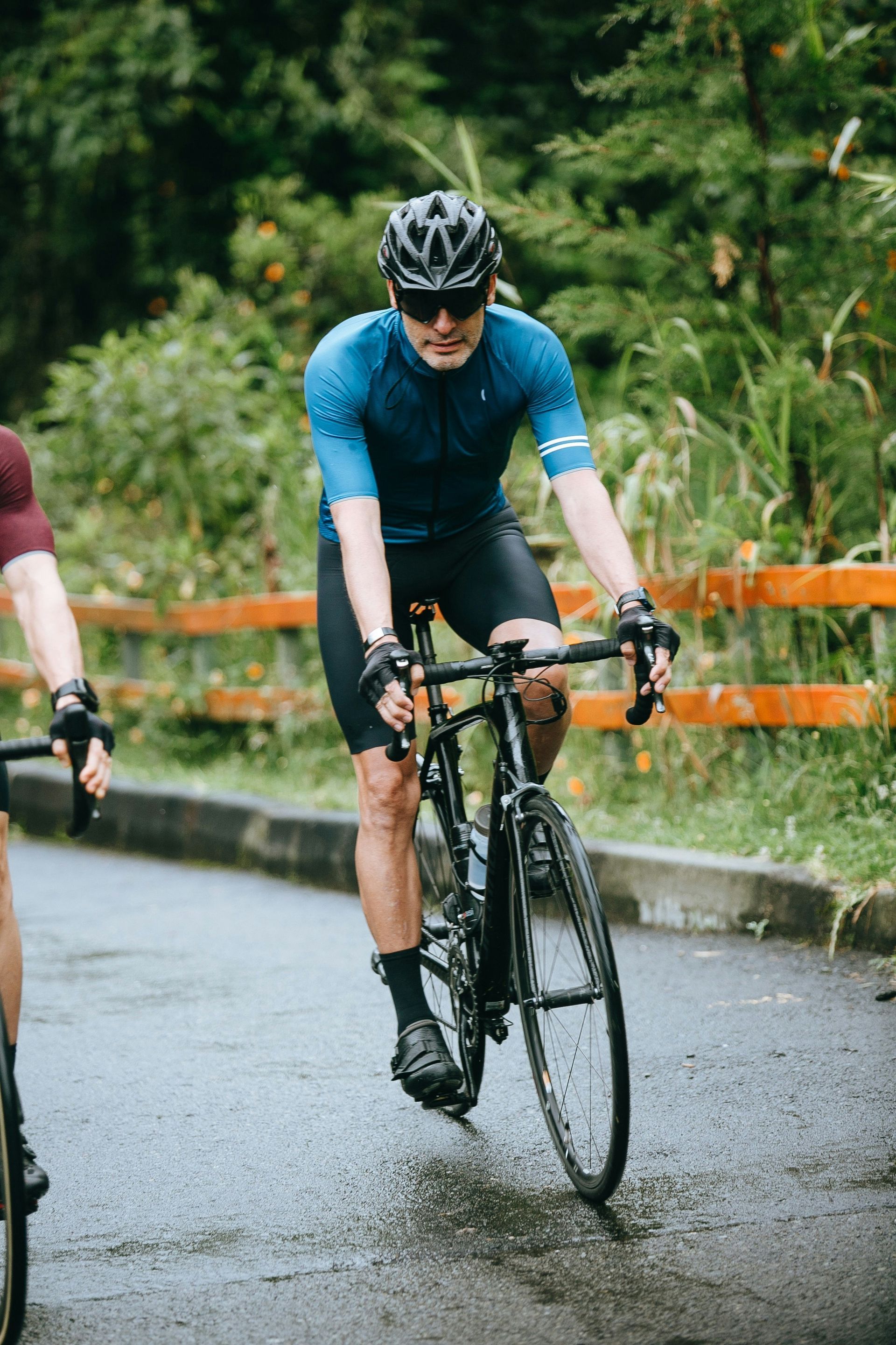Cyclist in Blue Jersey Rides Black Road Bike on Wet Road — EyeMax EyeCare in Lake Macquarie, NSW