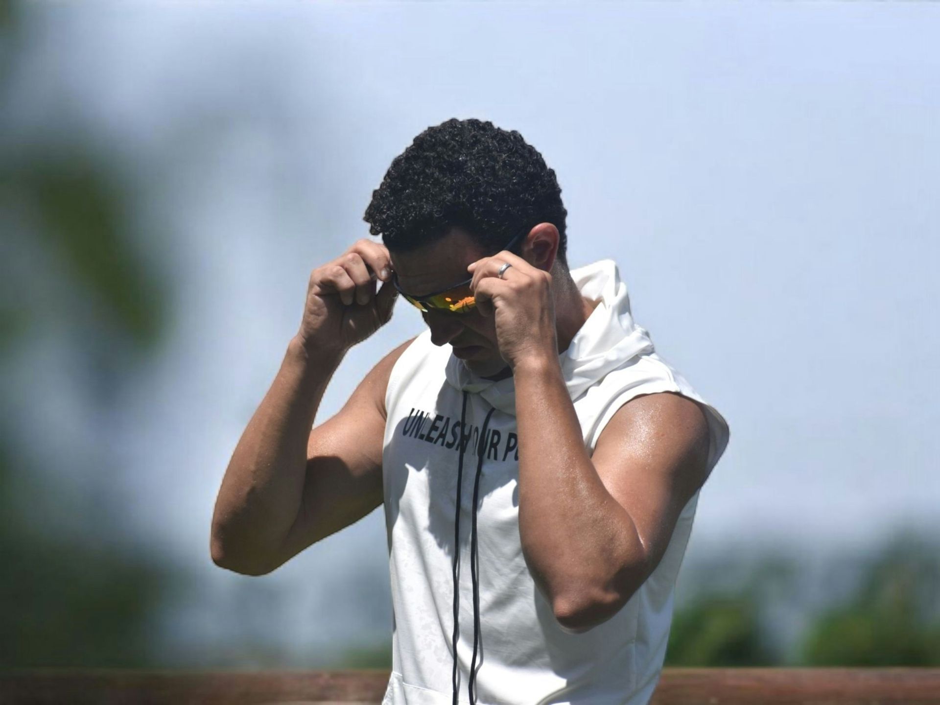 Man in a White Sleeveless Hoodie Adjusting Yellow Sunglasses — EyeMax EyeCare in Cessnock, NSW
