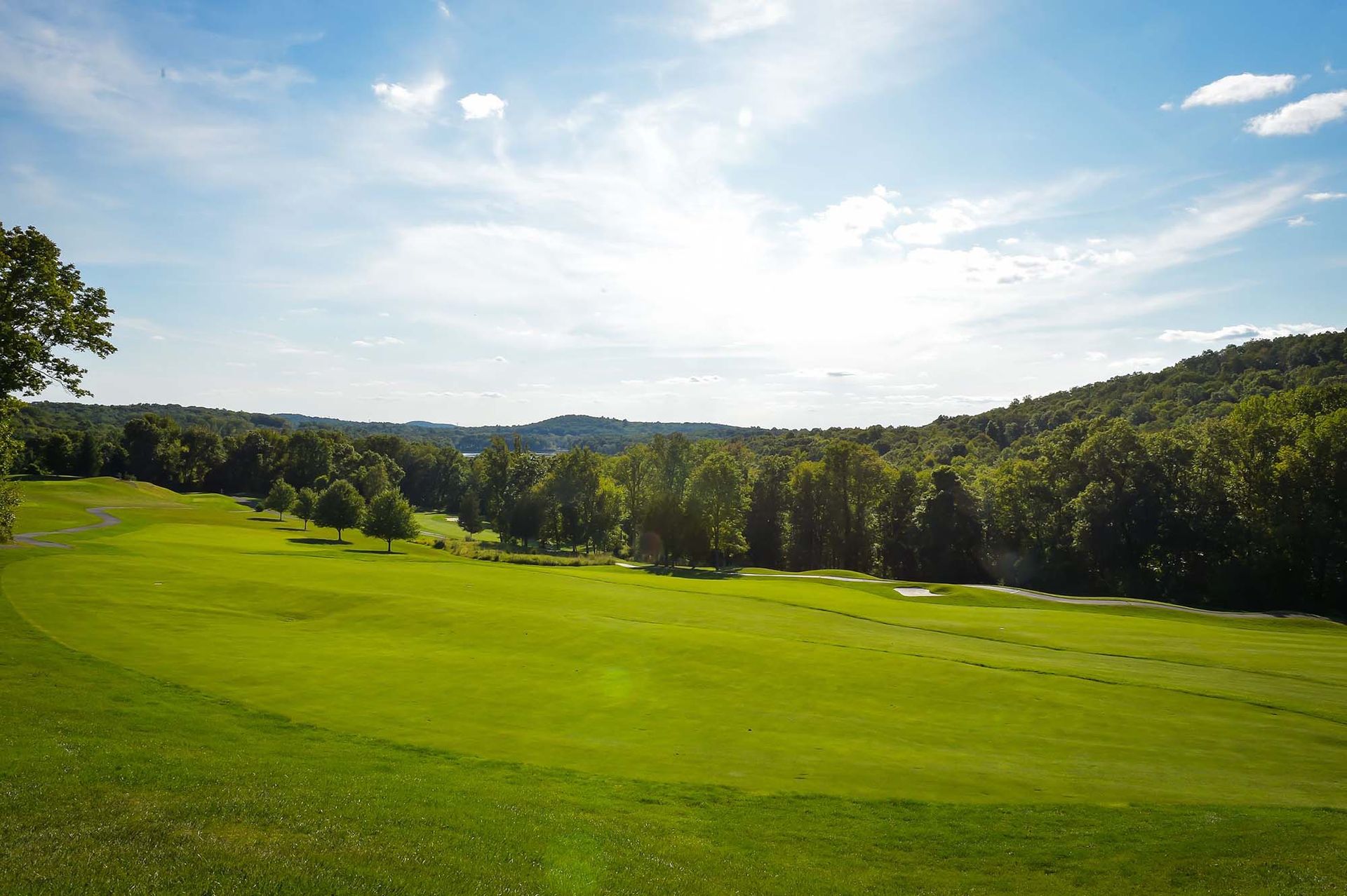 A golf course with a lot of green grass and trees in the background.