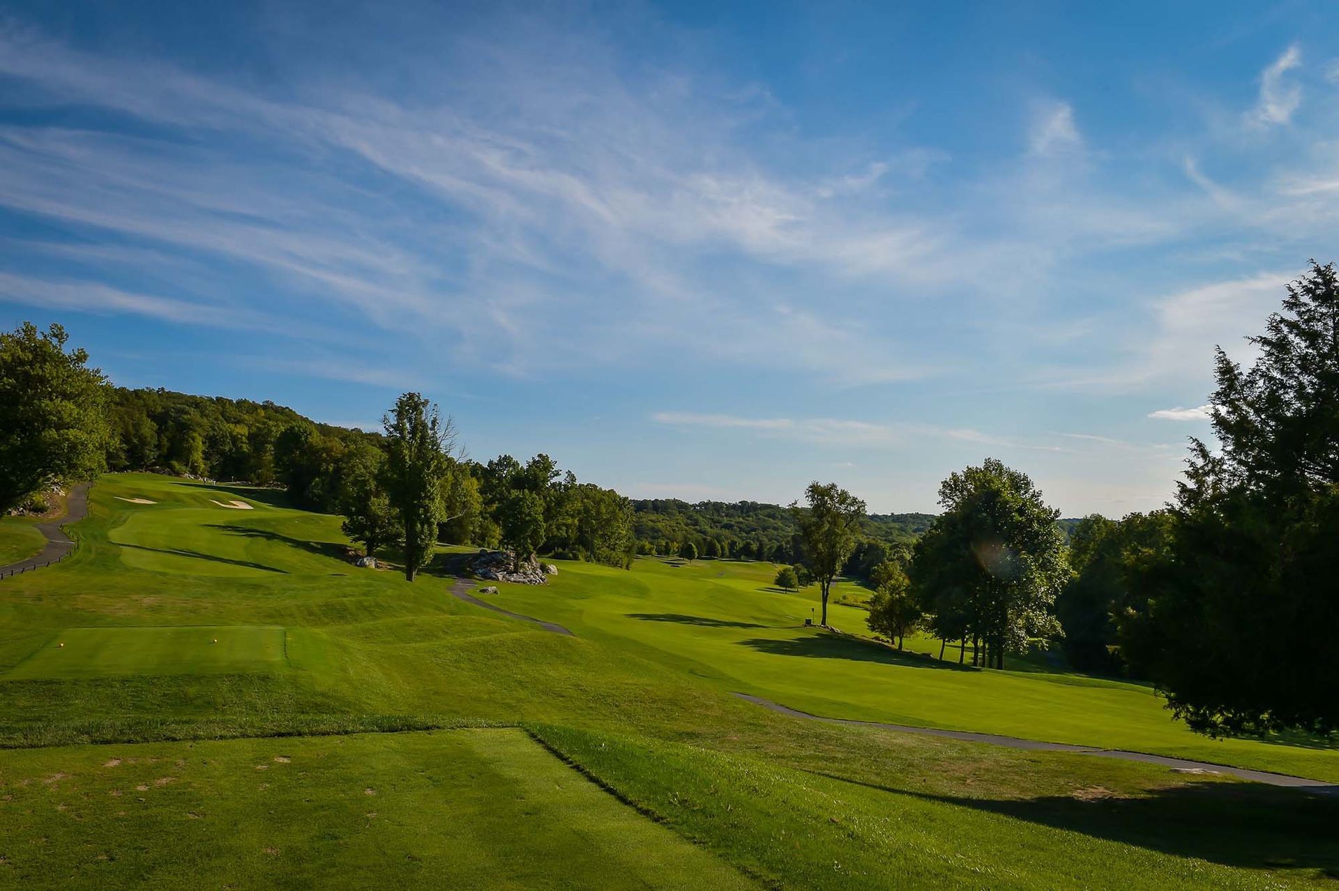 A golf course with trees and a blue sky in the background.