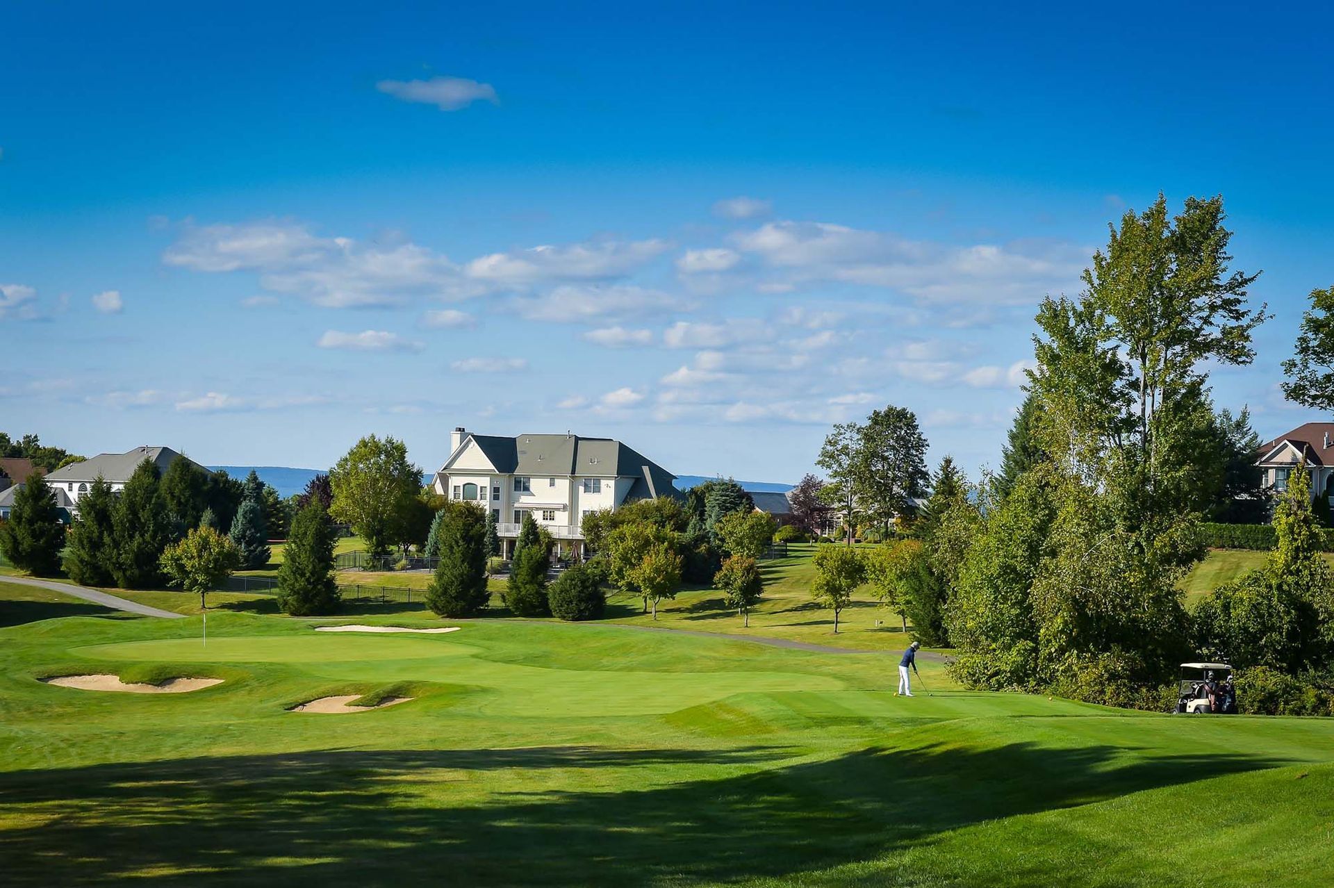 A golf course with a house in the background on a sunny day.