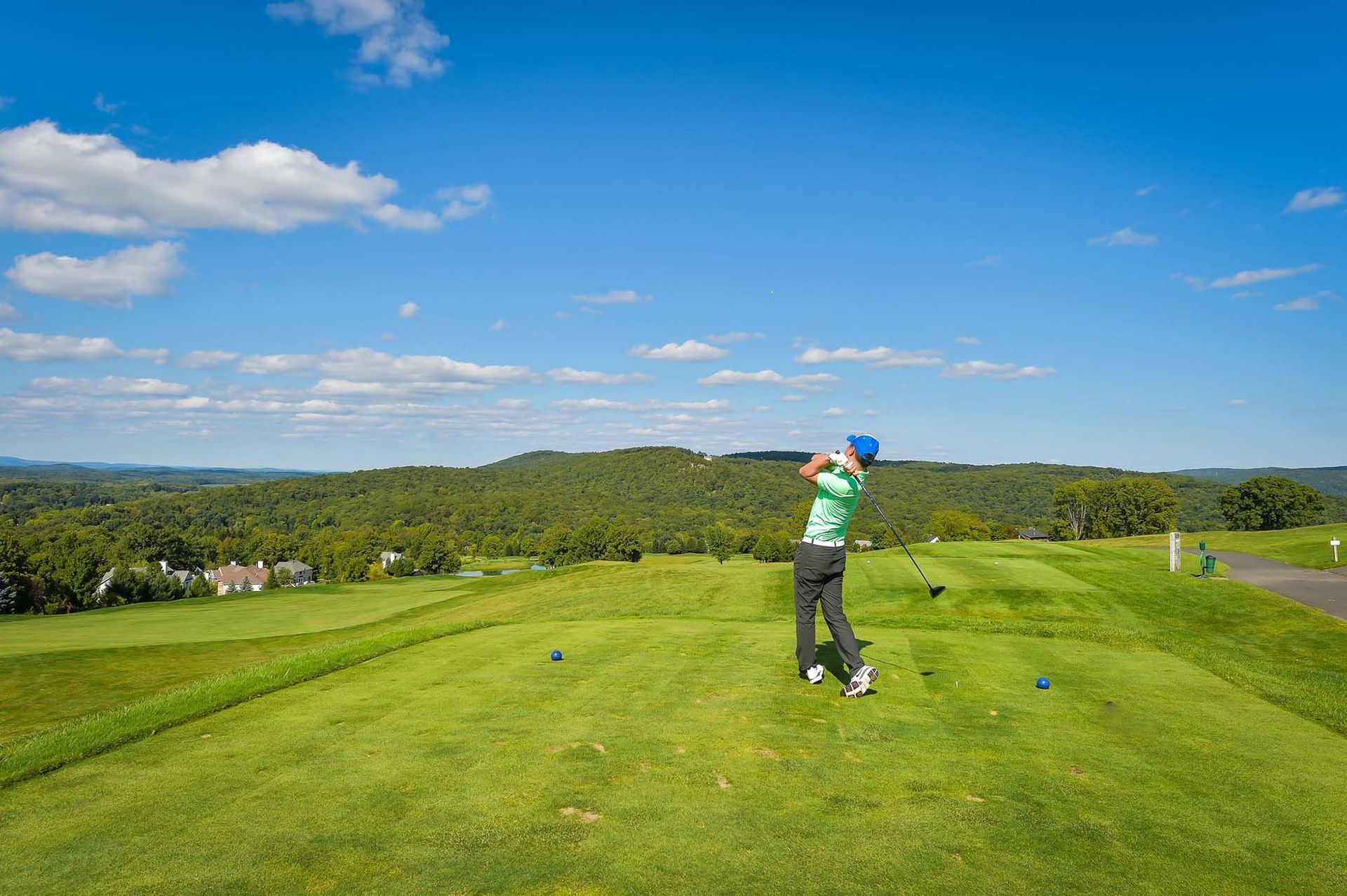 A man is swinging a golf club on a golf course.