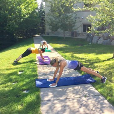 Two women are doing push ups on yoga mats on a sidewalk