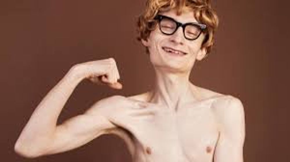 A shirtless man with glasses is flexing his muscles.