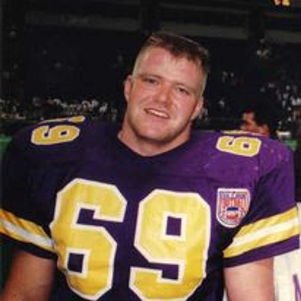 A man is wearing a purple and yellow football jersey with the number 69 on it.