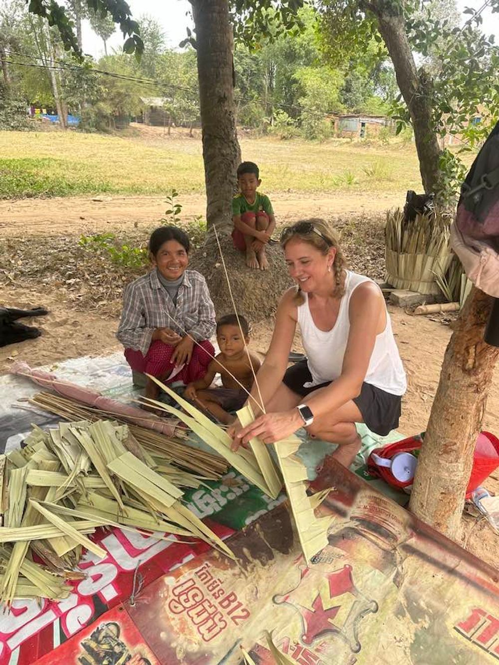 A woman is sitting on the ground making a basket.