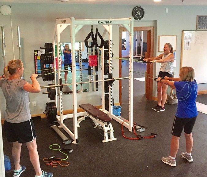 A woman in a blue shirt is doing squats in a gym