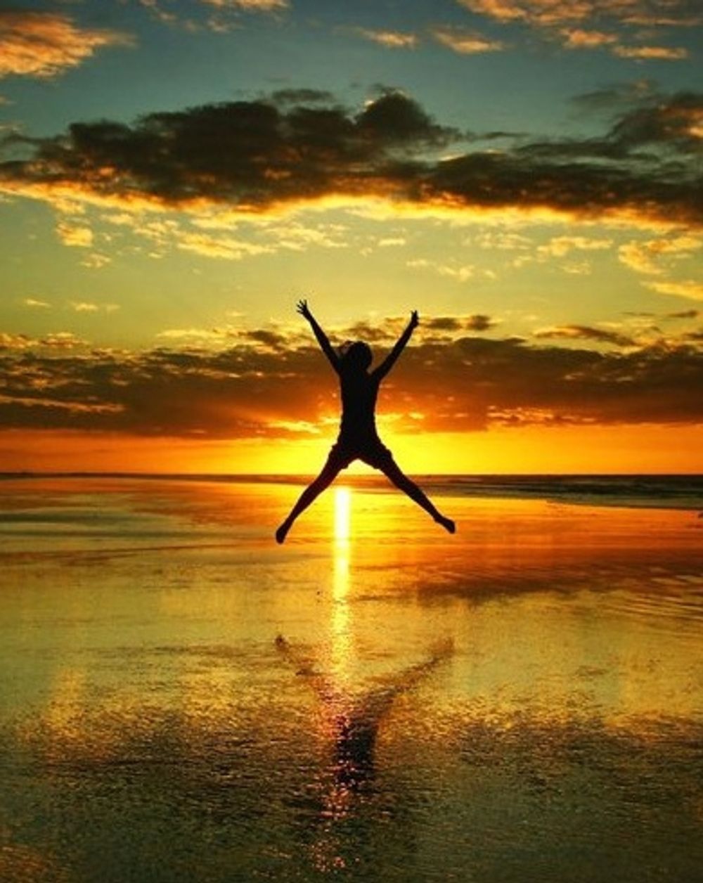 A silhouette of a person jumping in the air at sunset